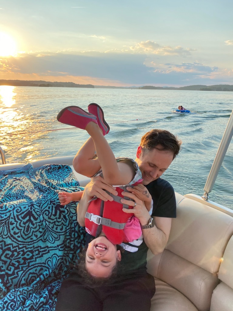 A person holding a baby in a body of water

Description automatically generated